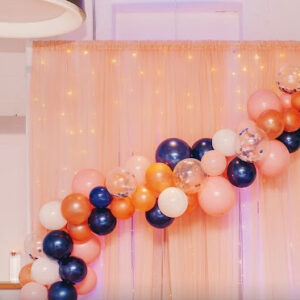 a balloon arch is decorated with blue, orange and white balloons