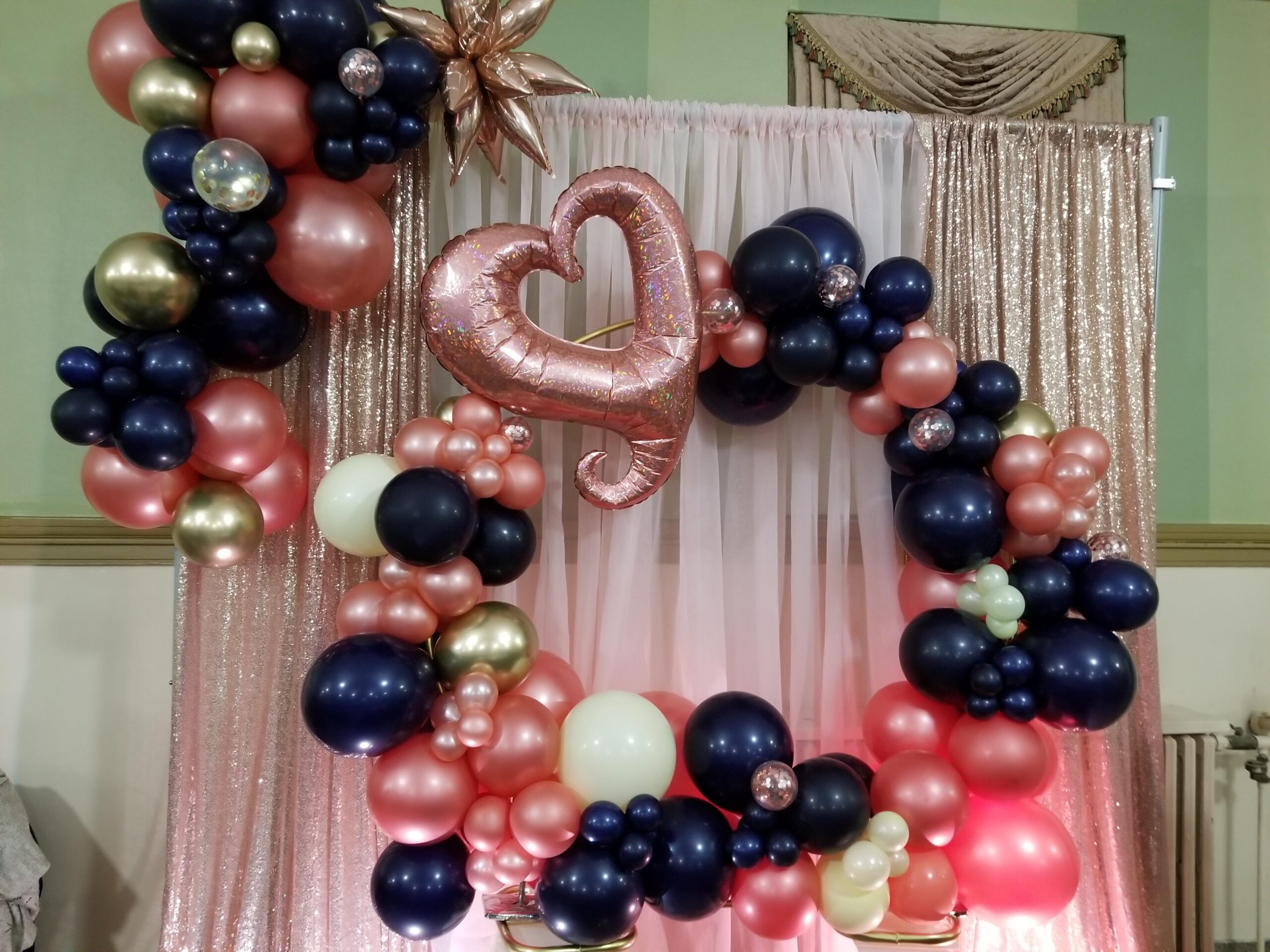 a balloon arch is decorated with pink, blue and gold balloons