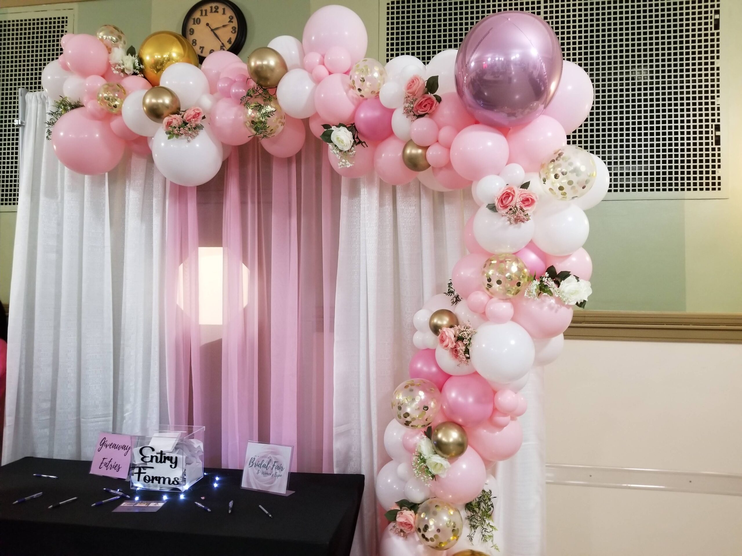 a pink and gold balloon arch with balloons