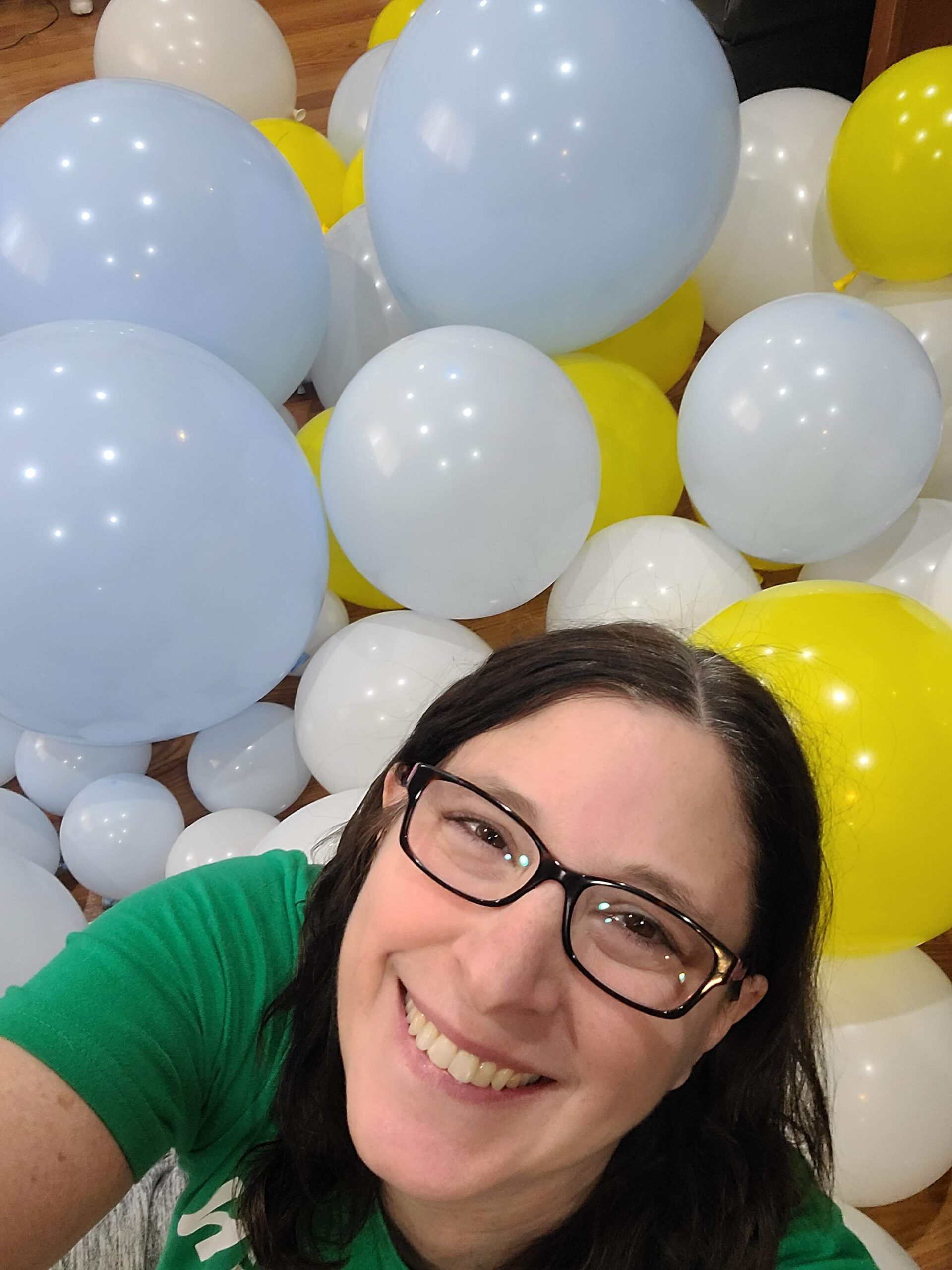 a woman with glasses is smiling in front of balloons