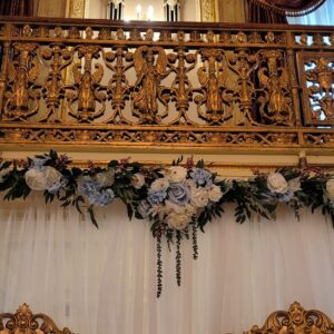 a gold and white wedding arch decorated with flowers