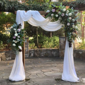 an outdoor wedding ceremony with white drapes and flowers