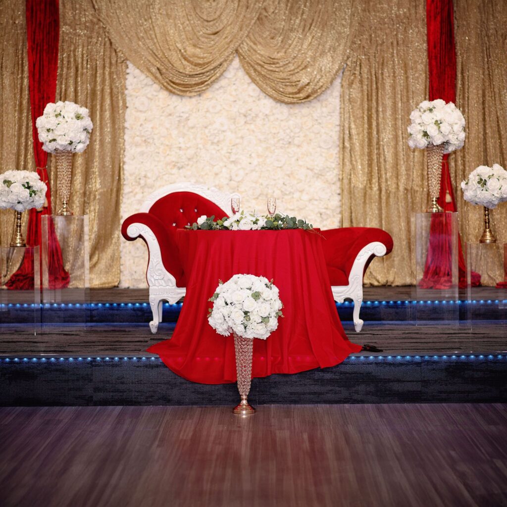 a red settee in front of a gold backdrop budget wedding
