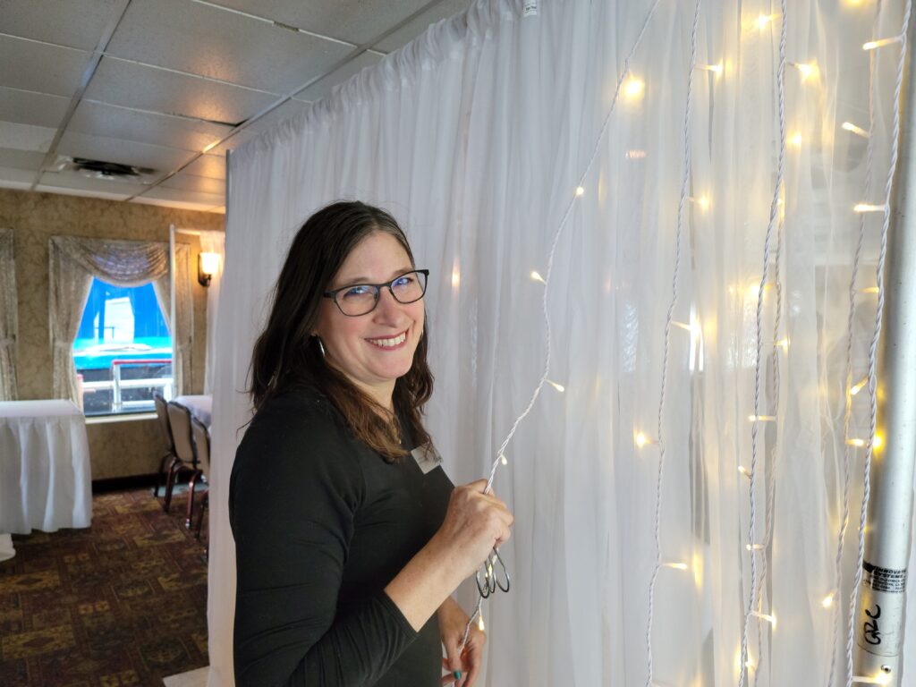 a woman is holding a pair of scissors in front of a curtain