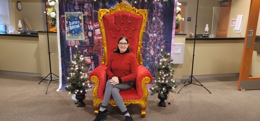 a woman sitting on a red chair in front of a christmas tree