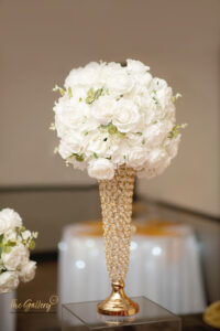 a gold vase filled with white flowers on top of a table