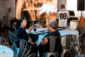 two women are sitting at a table talking to each other