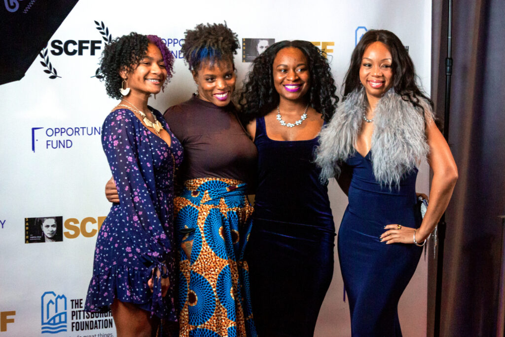 three women standing next to each other on a red carpet