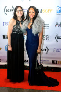 two women standing next to each other on a red carpet