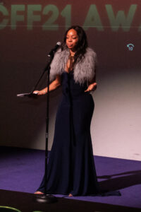 a woman standing at a microphone in front of a screen