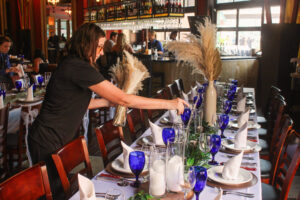 a woman setting a table with blue and white dishes