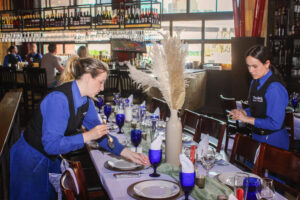 two women in blue aprons are setting a table