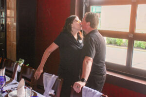 a man and woman kissing in front of a window