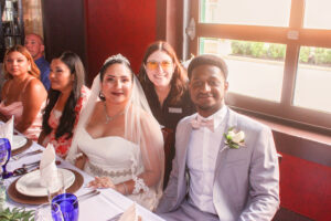 a bride and groom pose for a photo in front of their guests