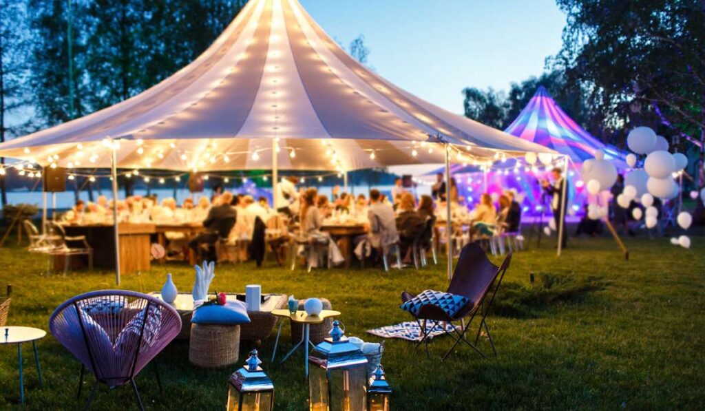 a large tent with lights and chairs in the grass