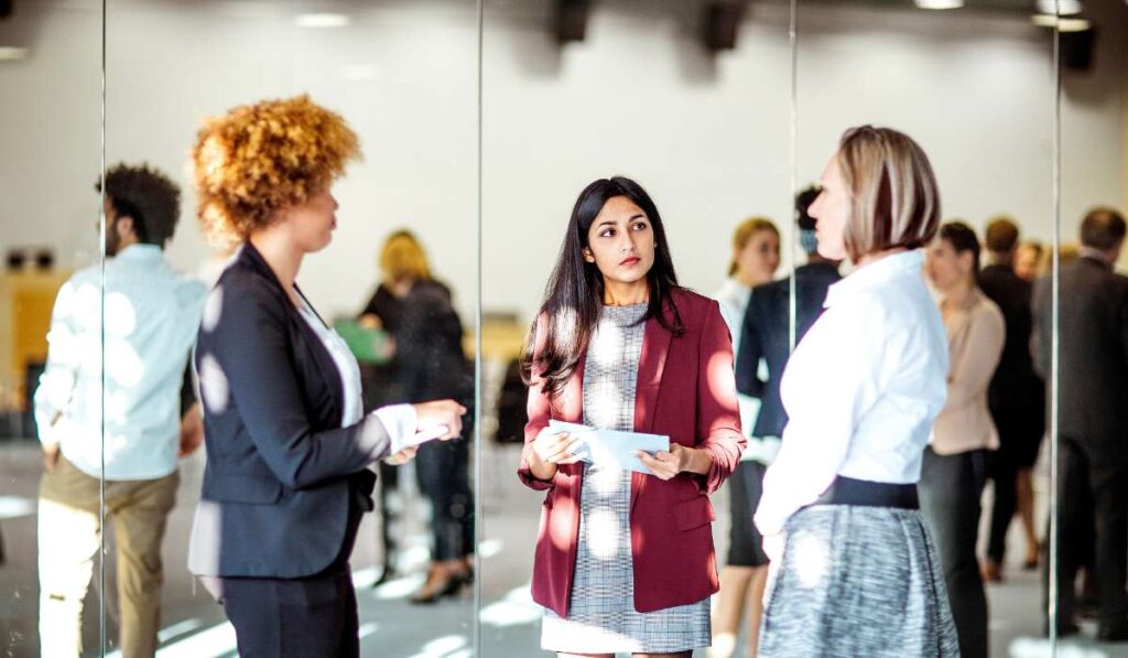 a woman standing in front of a mirror talking to another woman