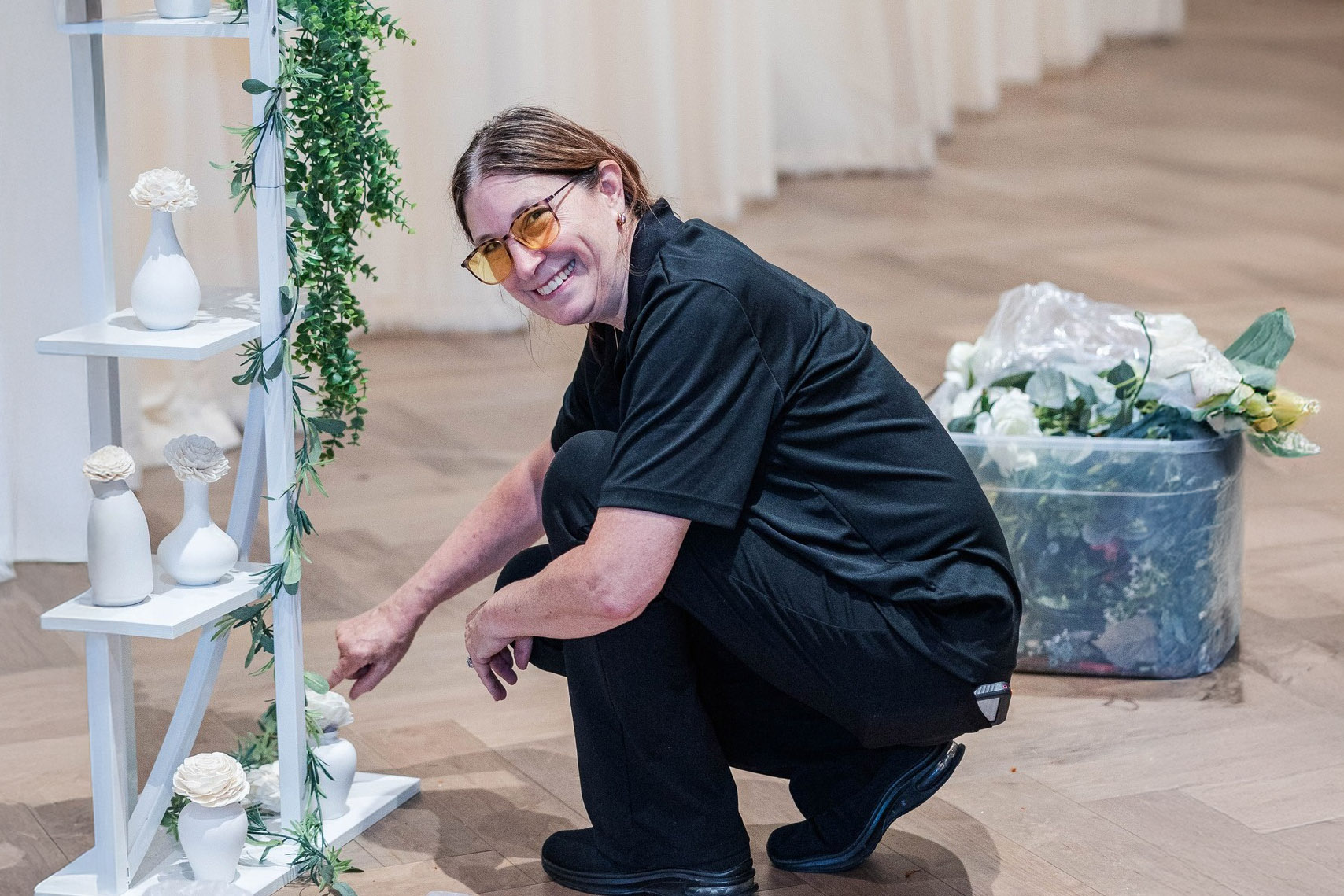 a man kneeling down next to a tall white shelf