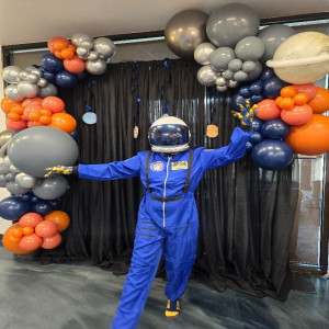 a man in a space suit standing in front of balloons