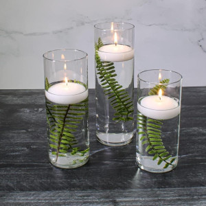 a group of three glass vases filled with candles