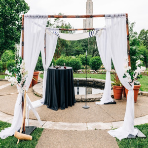 an outdoor ceremony setup with white drapes and black table cloths
