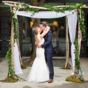 a bride and groom sharing a kiss under a wedding arch