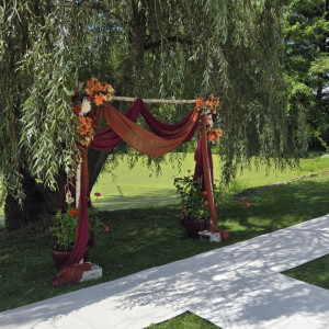 an outdoor wedding setup with a red and orange drape
