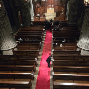a person walking down a red carpeted aisle in a church