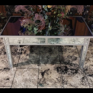 a mirrored table with a flower arrangement on top