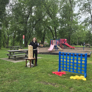 a woman standing in a park holding a board game