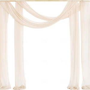 a white wedding arch decorated with sheer fabric