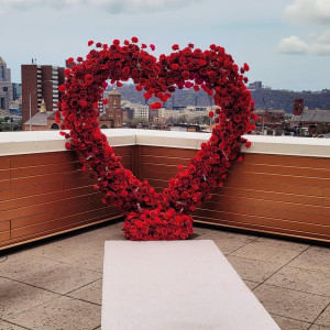 Large red rose heart arch backdrop on a rooftop in Pittsburgh overlooking the city skyline