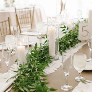 a long table with candles and greenery on it