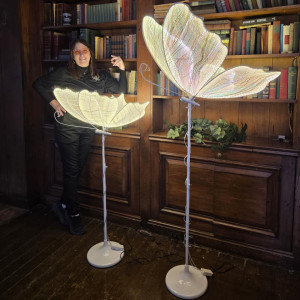 Large illuminated butterfly floor light glowing warmly beside elegant event draping and luxury décor setup